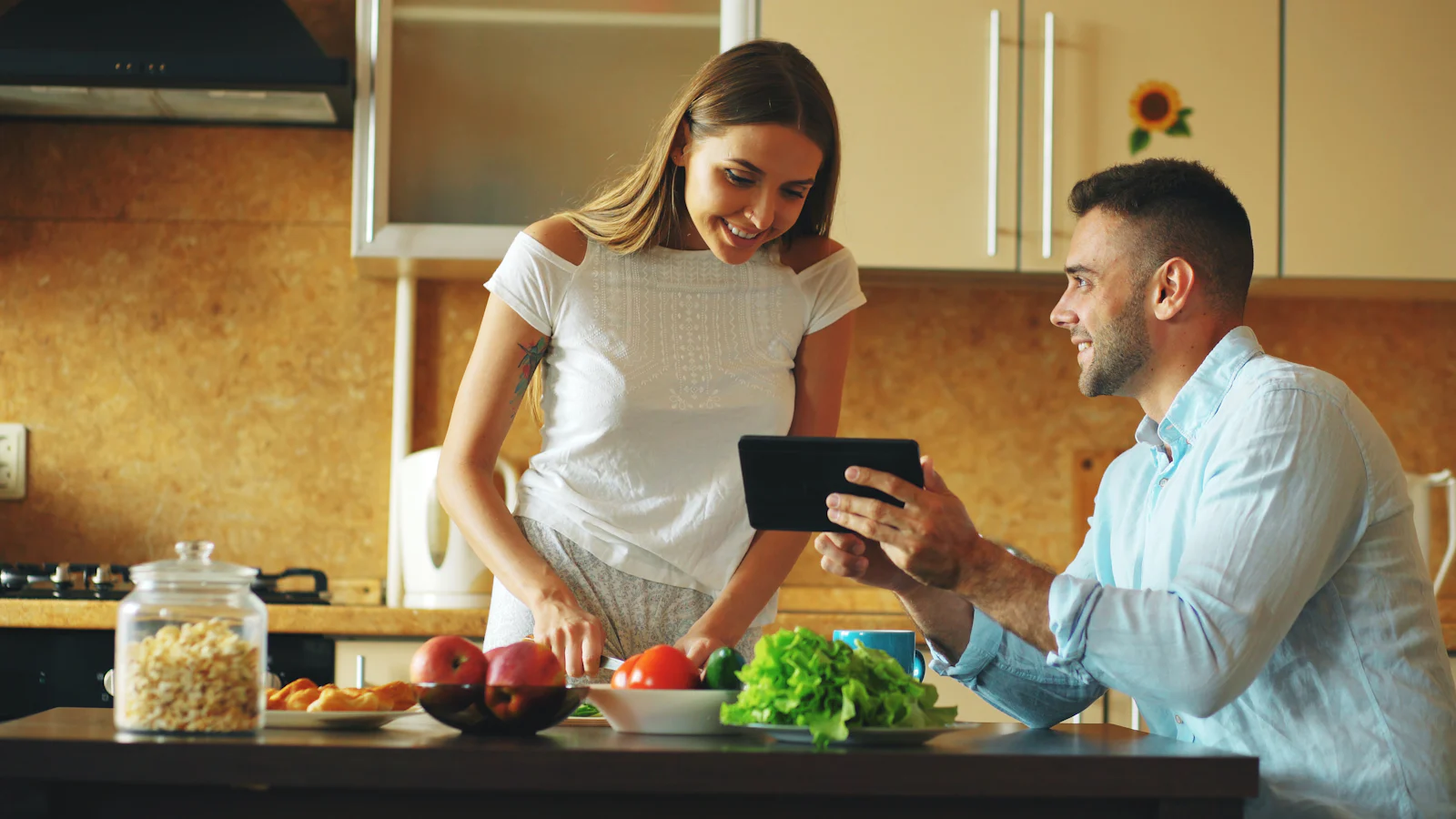 Tablet com uma receita aberta pousado numa bancada de cozinha, ao lado de ingredientes